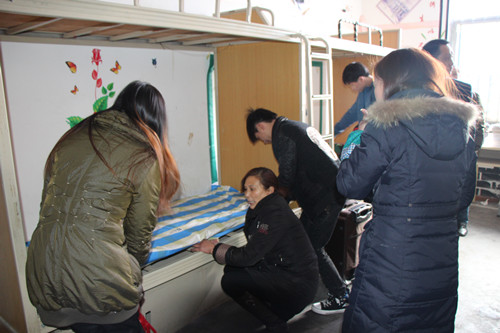 宿管老师为学生亲自整理床铺。